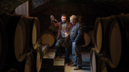 Men tasting wine in barrel room