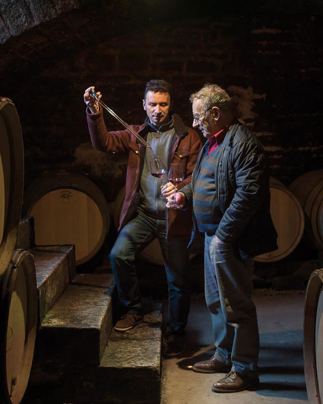 Men tasting wine in barrel room
