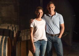 Emma and Rod standing next to wine barrels