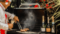 Sausage sizzle with champagne bottles sitting on top of BBQ
