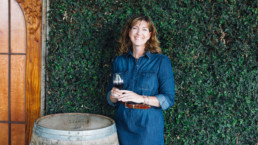 Woman standing next to wine barrel drinking wine