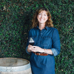 Woman standing next to wine barrel drinking wine