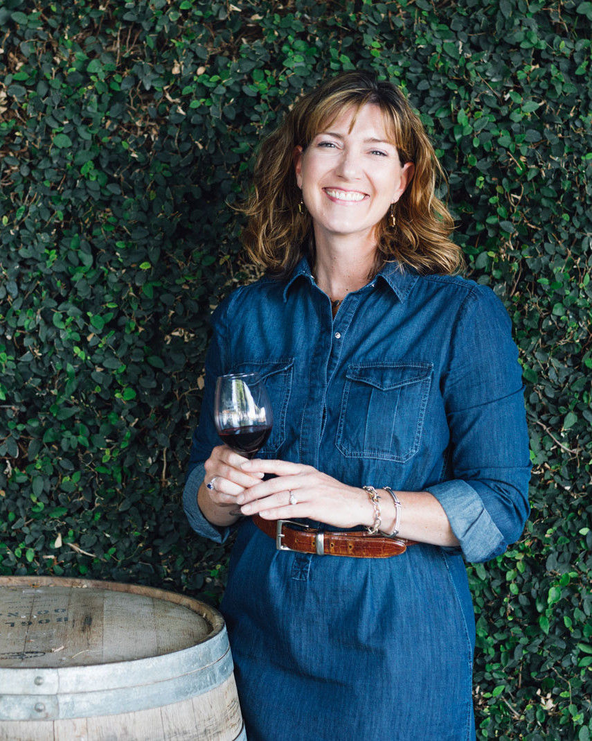 Woman standing next to wine barrel drinking wine