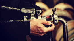 Close up of hands working a tap inside of the winery